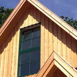 Innenaufnahme eines modernisierten Fachwerkhauses mit sichtbaren dunklen Holzbalken, weißer Holzdecke und einer stilvollen Hängeleuchte.