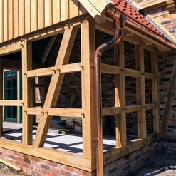 Detailansicht eines Holzanbaus mit robusten Trägern und Verstrebungen, exemplarisch für die präzise Arbeit einer Zimmerei.