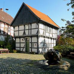 Sorgfältig restauriertes Fachwerkhaus, ein Beispiel für die kunstvolle Arbeit einer Zimmerei, mit einem Brunnen im Vordergrund.