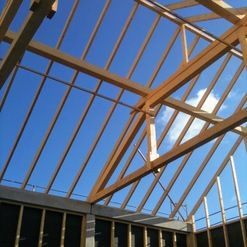 Konstruktion eines Holzdachstuhls unter klarem blauem Himmel, demonstriert die präzise Arbeit einer Zimmerei.