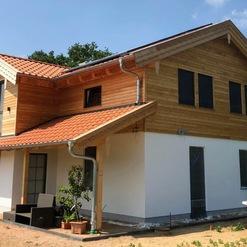 Neubau eines modernen Einfamilienhauses mit Holzverkleidungen und Ziegeldach, zeigt die fachmännische Arbeit einer Zimmerei.