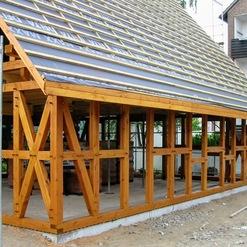 Aufbau eines Holzdaches mit offener Struktur, zeigt die präzise und robuste Arbeit einer Zimmerei während der Montage.