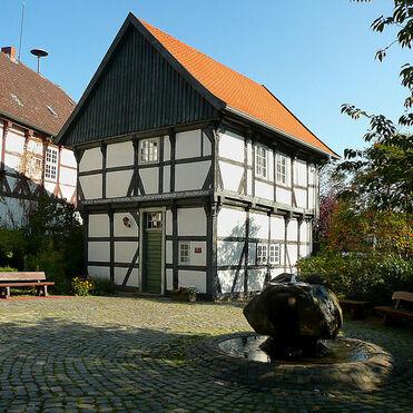 Sorgfältig erhaltenes Fachwerkhaus, ein klassisches Beispiel für traditionellen Fachwerkbau, mit einem Brunnen im gepflasterten Hof.