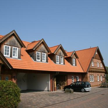 Reihe moderner Fachwerkhäuser mit charakteristischen Holzelementen und Ziegeldächern, die den traditionellen Fachwerkbau modern interpretieren.