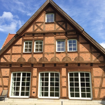 Ein liebevoll restauriertes Fachwerkhaus mit Ziegelverblendung, Holzstützen und großen Fenstern, zeigt klassischen Fachwerkbau.