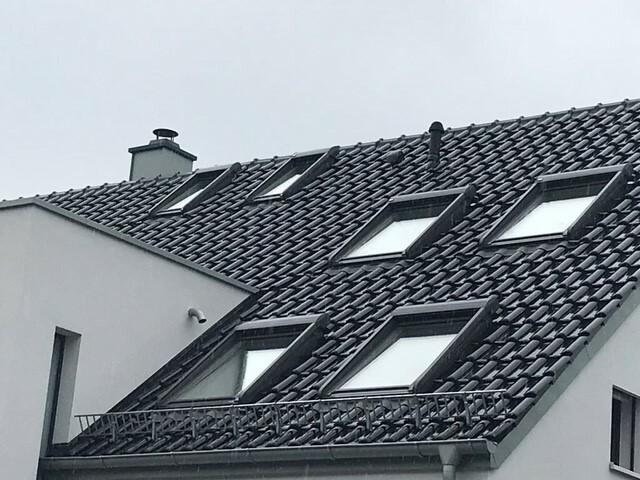 Blick auf ein Dach mit schwarzen Dachziegeln und 6 Velux-Fenstern