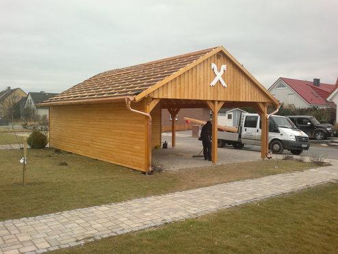 Ein frisch errichteter Holz-Carport mit einem Ziegeldach und dekorativen Kreuzmotiven, bereit zur Nutzung auf einem Wohngrundstück.